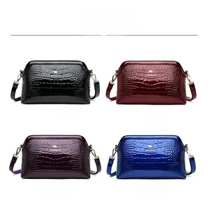 Detail view of glossy crocodile embossed handbags in black, red, purple and blue