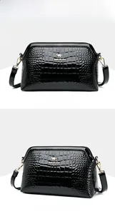 Close-up of black patent leather crossbody bag with crocodile pattern and gold hardware