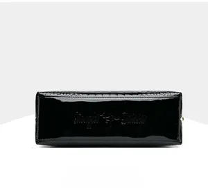 Detail view of glossy black faux crocodile embossed patent leather handbag base
