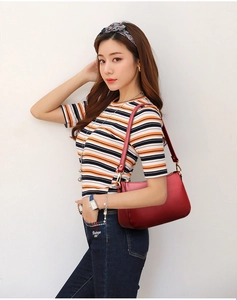 Detail of dark red lychee grain leather shoulder bag with golden hardware and zipper