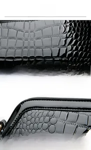 Detail view of black crocodile pattern patent leather handbag and stitching quality