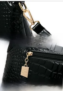 Detail of glossy black crocodile texture bag with golden metal kangaroo logo zipper