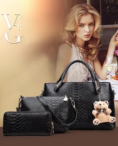 Detailed view of 3-piece black tote set with crocodile pattern and bear pendant charm
