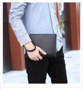 Close-up of a brown leather men's clutch bag with embossed logo and a wrist strap