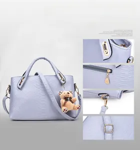 Detail view of lavender faux snake skin handbag showing metal buckle and plush bear charm