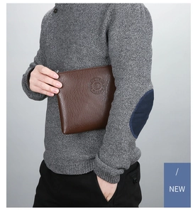 Detail of dark brown pebble grain leather clutch bag with a round embossed logo