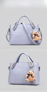 Detail of light purple crocodile texture handbag with cute brown plush bear charm