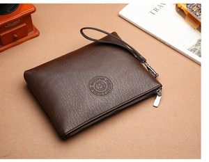 Close-up of dark brown lychee texture leather clutch with wrist strap and zipper detail