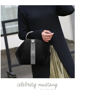 Detail of woven texture handbag featuring vertical silver rhinestone strips and metal handle
