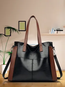 Détail d'un sac cabas noir et marron avec doubles poignées et finitions argentées