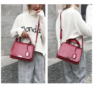 Détail d'un sac à main rouge vintage porté en bandoulière et à la main avec boucle métal