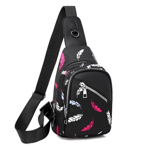 Detail of black oxford chest bag featuring colorful feather prints and silver zippers