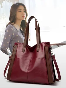 Vue détaillée du sac cabas bordeaux avec anses marron et boucles métalliques argentées
