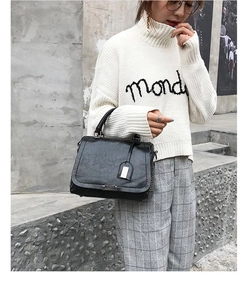 Gros plan d'un sac à main noir en similicuir grainé porté dans un style décontracté