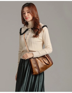 Grand sac à main en cuir marron porté par un mannequin en pull beige et jupe verte