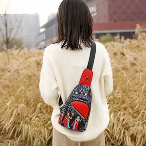 Close-up of ethnic print sling bag with red leather trim and metal zipper details