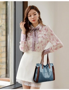 Détail du sac fourre-tout bicolore bleu et marron porté par un mannequin en tenue fleurie