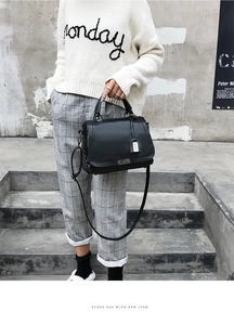 Détail du sac à main en cuir noir avec rivets argentés et bandoulière sur un mannequin