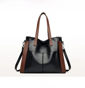 Vue de face d'un grand sac cabas en cuir verni noir avec garnitures et poignées contrastées brunes