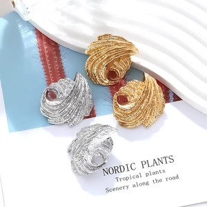 Macro detail of asymmetric leaf-shaped gold and silver earrings with wave texture