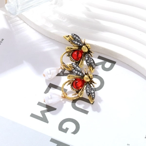 Détail de boucles d'oreilles abeille vintage avec gemmes rouges et perles blanches