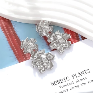 Close-up of silver double-layer flower earrings with textured irregular metal petals