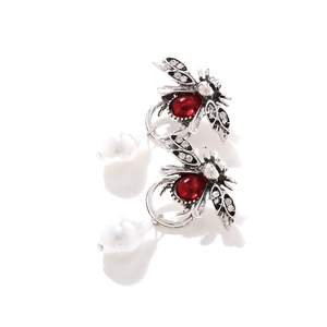 Détail de boucles d'oreilles abeille vintage avec cristaux rouges et perle baroque