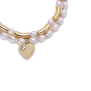 Detail of layered pearl necklace featuring gold curved tubes and a small heart pendant