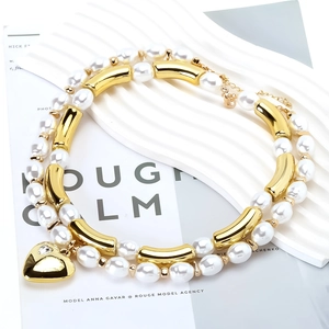 Double-layer pearl and gold bead necklace with a zircon heart pendant on a white platform