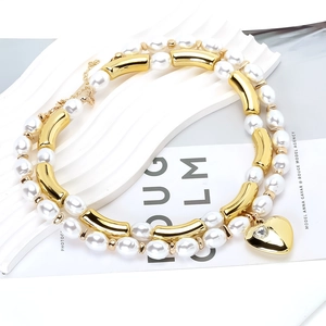 Macro detail of multi-layer pearl necklace with gold heart pendant and zircon stone