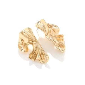 Macro detail of chunky gold wave earrings featuring an irregular geometric crinkled texture