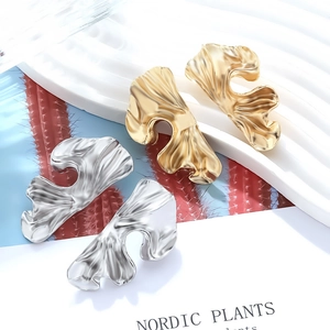 Macro detail of gold and silver textured alloy earrings with abstract leaf shapes