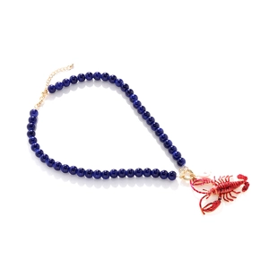 Detailansicht der tiefblauen Perlenkette mit rotem Hummer-Anhänger und goldenem Verschluss