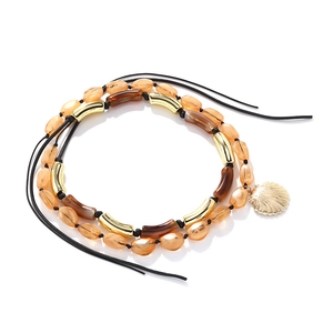 Detail of bohemian layered necklace with amber resin beads and golden seashell charm