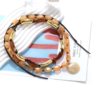 Detail of bohemian layered necklace with amber resin beads and gold seashell pendant