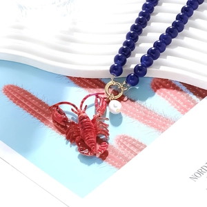 Detail der Perlenkette mit rotem Hummer-Anhänger und weißem Barockperlen-Akzent