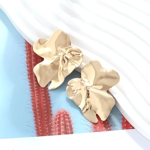 Vue macro de boucles d'oreilles feuilles dorées aux pétales irréguliers polis et texture rétro