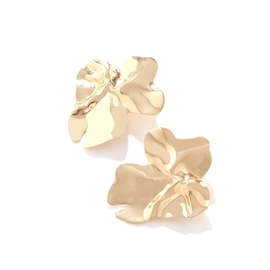 Détail de boucles d'oreilles dorées en métal aux feuilles irrégulières et brillantes