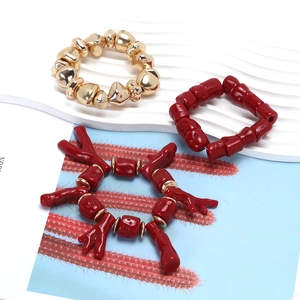 Detail of handmade resin coral beaded bracelets with red and gold irregular stackable beads