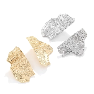 Macro detail of irregular textured gold and silver earrings with modern artistic design