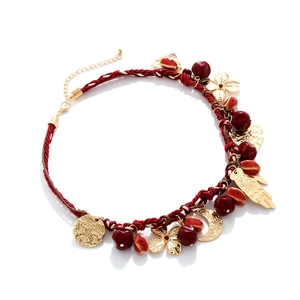 Detail of bohemian woven necklace featuring red rope with gold Hamsa and moon charms