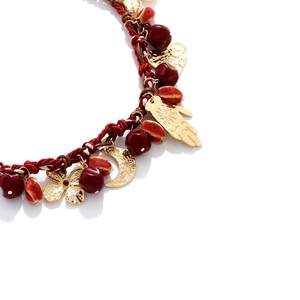 Detail of woven rope necklace with gold Hamsa hand, moon, and heart pendants