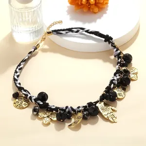 Detailed shot of ethnic braided necklace with Hamsa hand, sun, and moon gold-tone charms