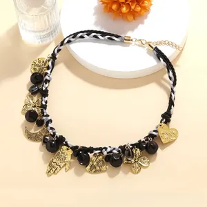 Detail view of woven beaded necklace with golden hamsa hand and crescent moon charms