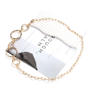 Macro detail of gold-tone geometric belt chain with hammered textured metal rings