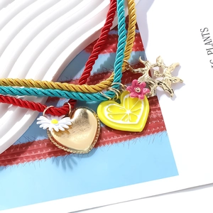 Detail of colorful woven cords with gold heart, daisy, and lemon slice charms set