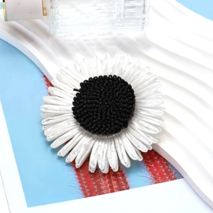 Handmade knitted sunflower hair clip with white petals and black center on a blue display