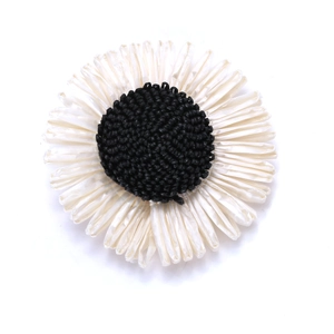 Detail of handmade woven sunflower clip with black core and white pleated petals