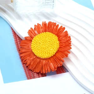 Handmade woven sunflower hair clip with vibrant orange petals and a yellow core centerpiece