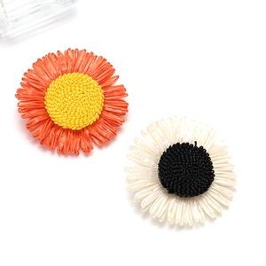 Close-up of handmade woven sunflower hair clips in orange and cream white colors